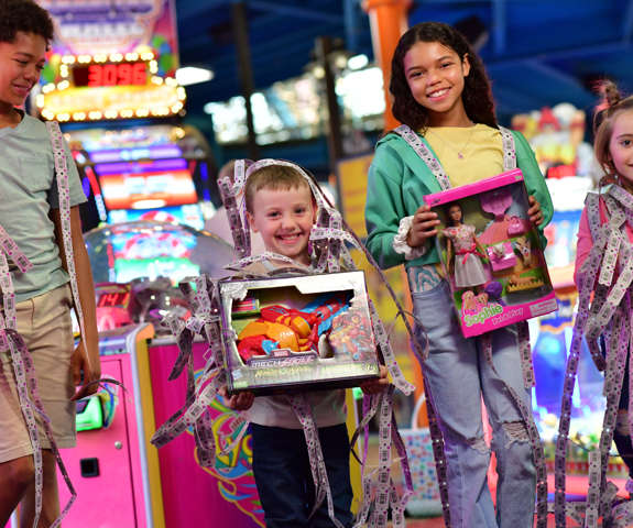 Kids showing of their prize shop winnings covered in tickets